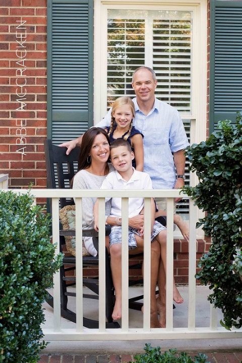 family posing on front porch of old house before moving to new home