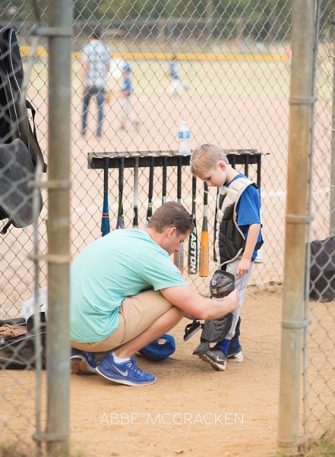 South Charlotte Recreation Association youth sports - a father helping his son gear up for baseball catcher
