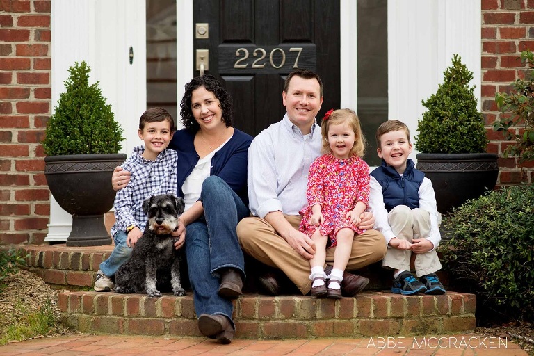 family posed at their front door with dog