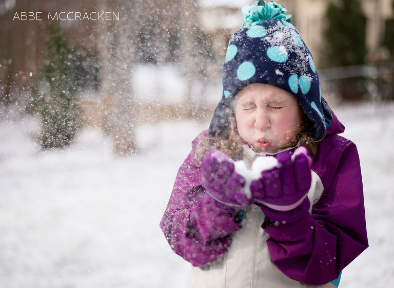 Child blowing white, powdery, magical snow from her hands
