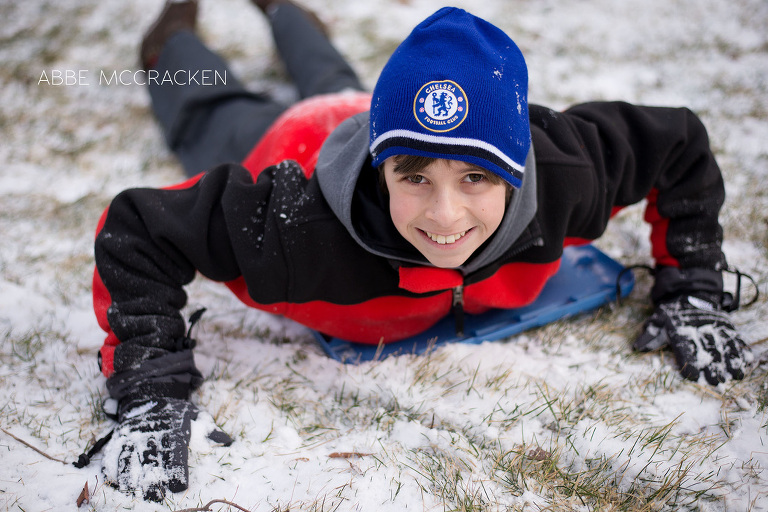 teen boy sledding in the snow on box tops
