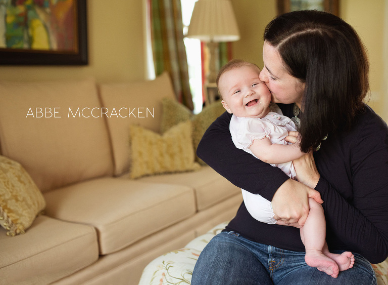 mommy and me photography session - a mother at home kissing her smiley 4 month old baby girl