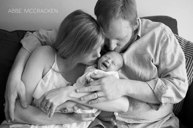 family of 3 - smiling newborn safe in parents arms
