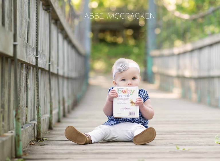 one year old baby girl teething on her favorite book
