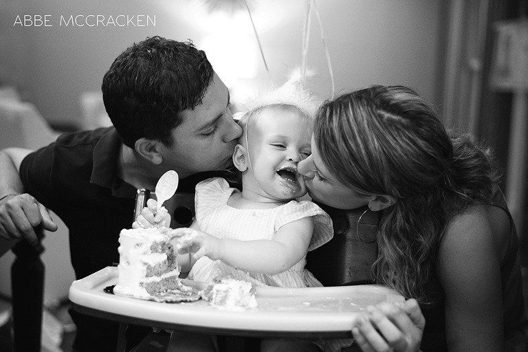 mom and dad kissing the birthday girl after first birthday smash cake