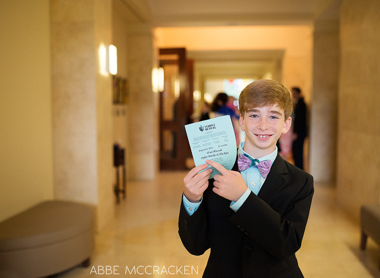 Jewish boy pointing to his name on Bar Mitzvah program