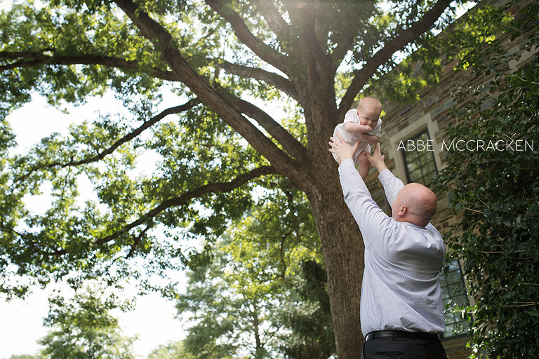 father tossing six-month old son in the air after christening