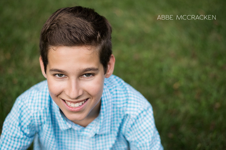 teen boy sitting in the grass smiling