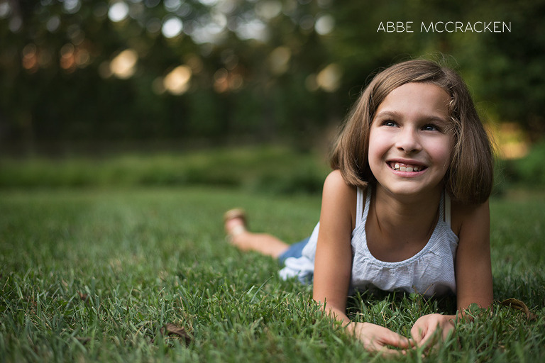 young girl laying on her tummy day dreaming in her backyard