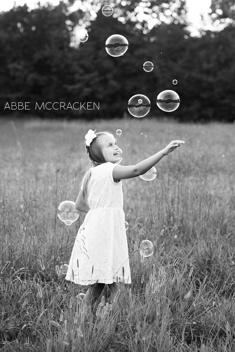 a girl in a field catching huge bubbles