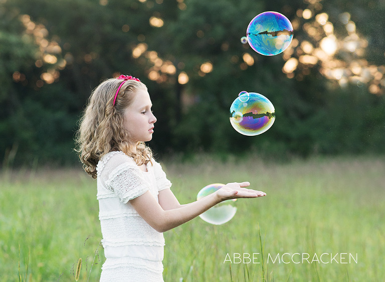 Child playing with bubbles in a field of tall grasses