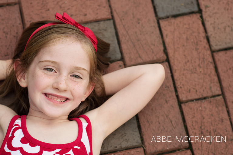 adorable red headed girl lying on red bricks