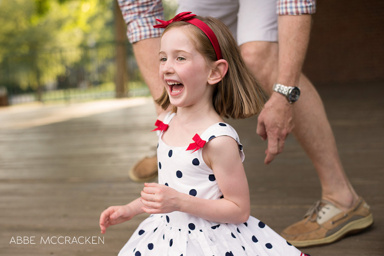 red headed girl giggling as father approaches from behind ready to tickle her