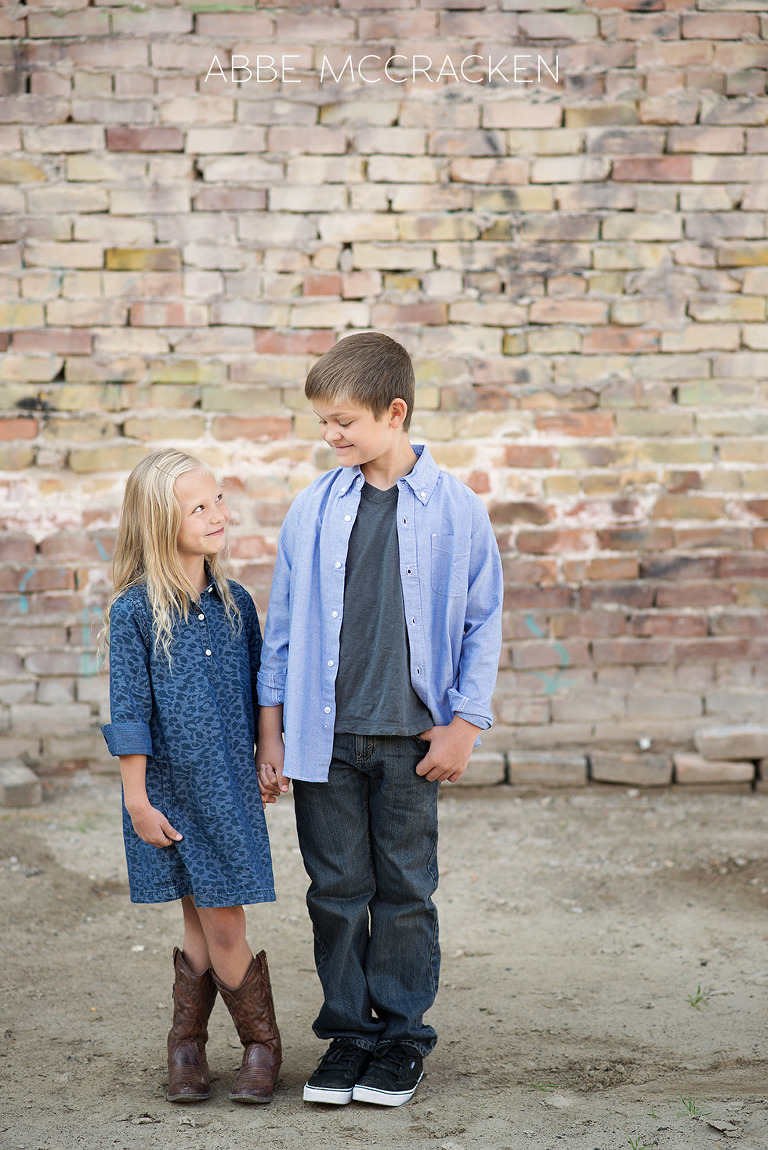 full body shot of siblings, kids against a unique brick wall