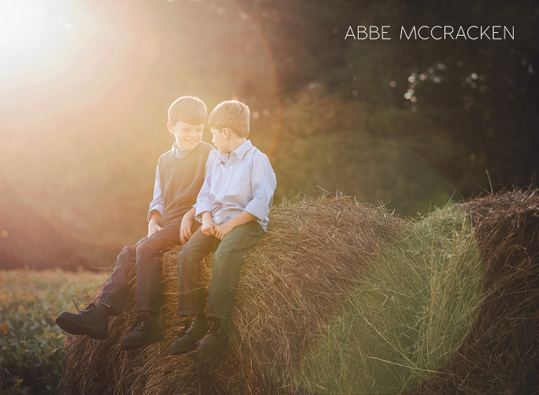 children sitting on hay bales with gorgeous sun flare