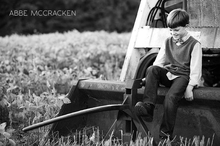 boy in a bowtie sitting on a tractor at family farm