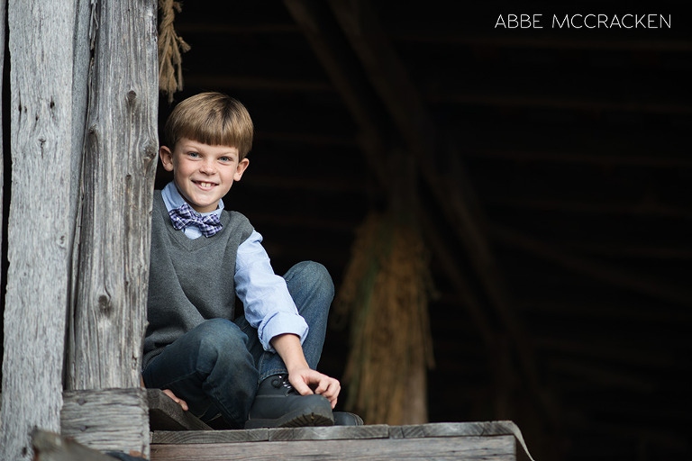 boy sitting on the 2nd floor of a barn at his family farm