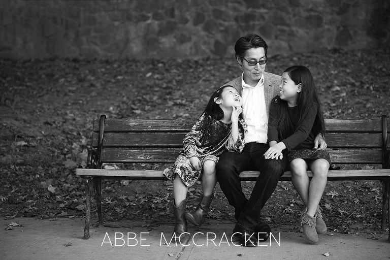 Daddy and his girls sitting on a park bench