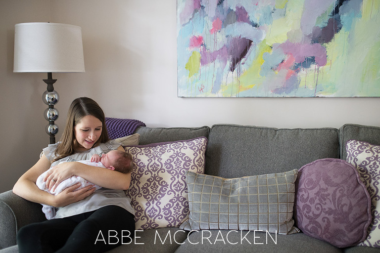 a mother and her newborn baby girl snuggling at home on the couch