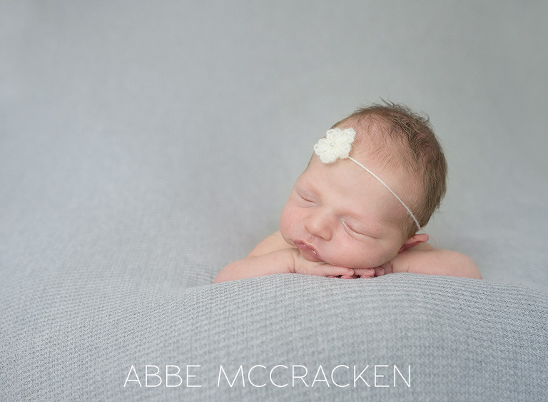 newborn baby girl resting her head on her hands
