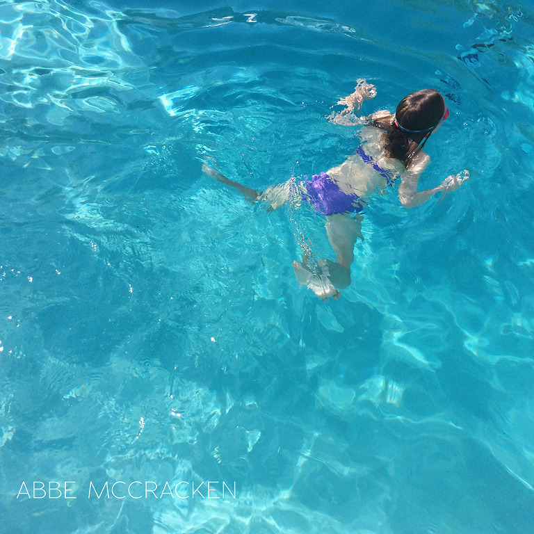 girl swimming in crystal clear blue pool taken with iPhone