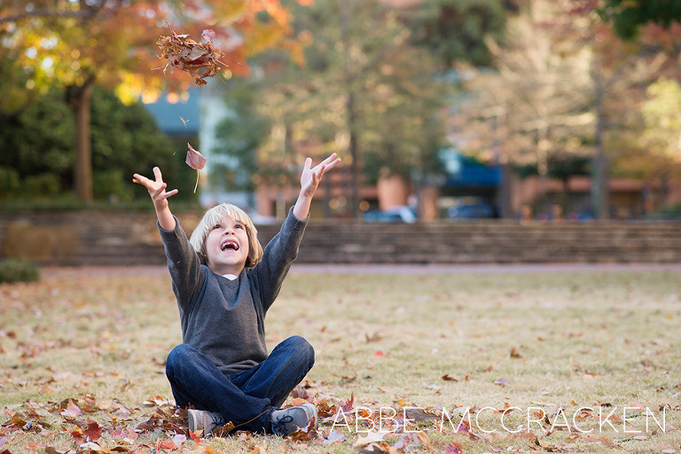 children's portraits in uptown Charlotte, NC - young boy throwing leaves