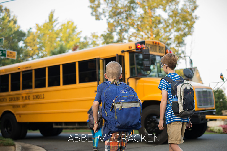 Back to School in Charlotte NC - young boy wearing his backpack walking towards school bus by Abbe McCracken