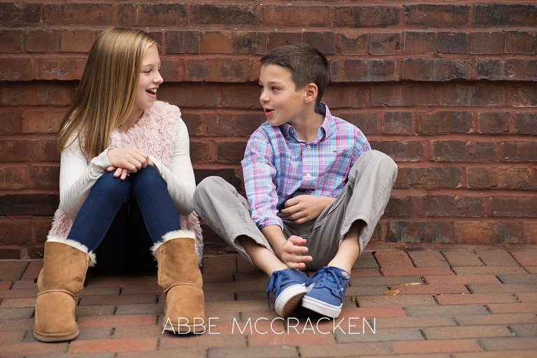 Siblings sitting against an urban brick wall in Uptown Charlotte, NC