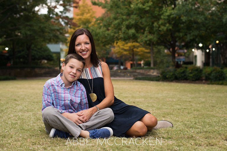 portrait of a mother and son sitting in the grass amongst the urban spaces of Uptown Charlotte