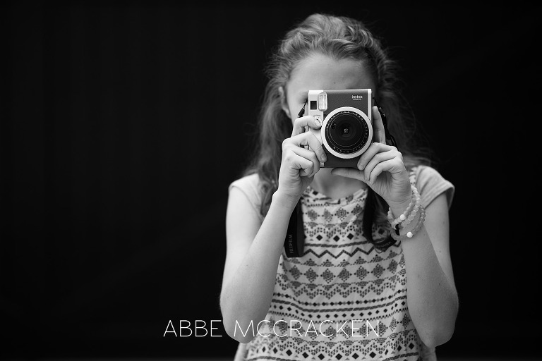 black and white portrait of a tween girl with a Fuji Instax Mini 90