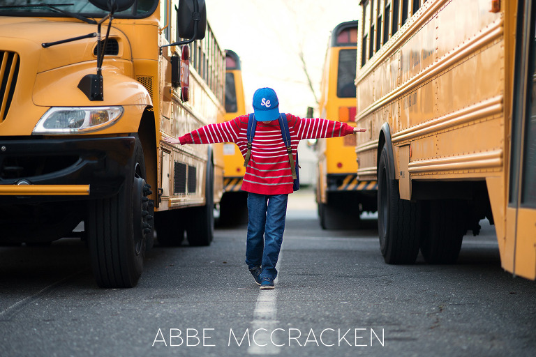 School boy pretending to walk a tight rope between Charlotte Mecklenburg school buses.