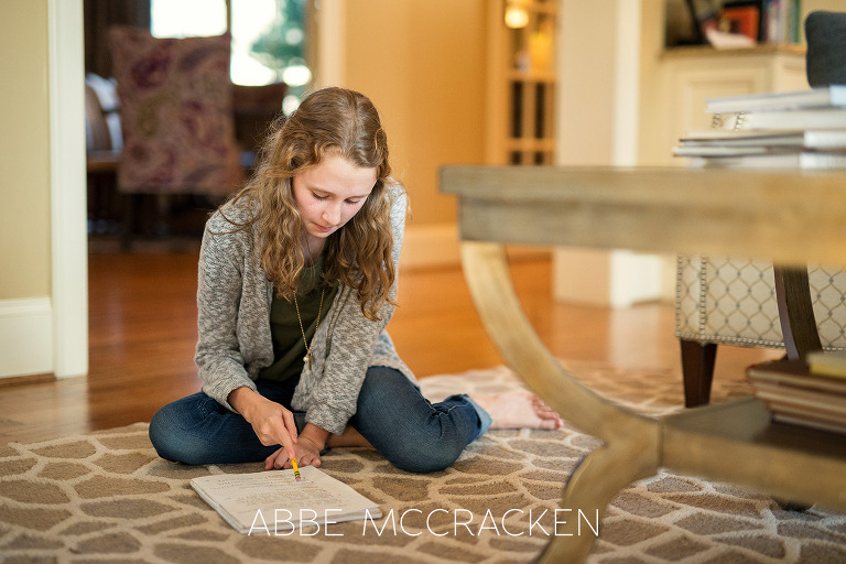 Young girl sitting on the floor at home studying