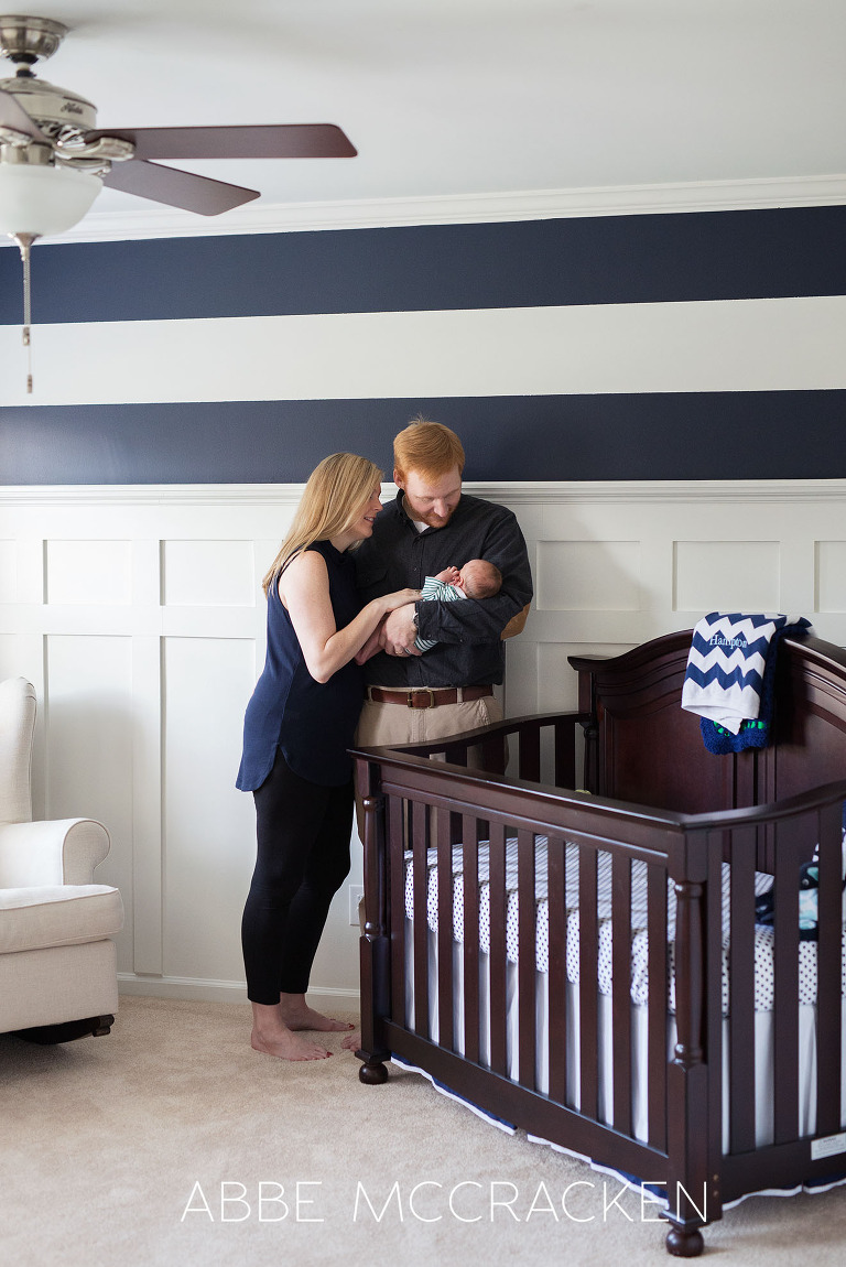 Parents cradling their new baby boy in his nursery room