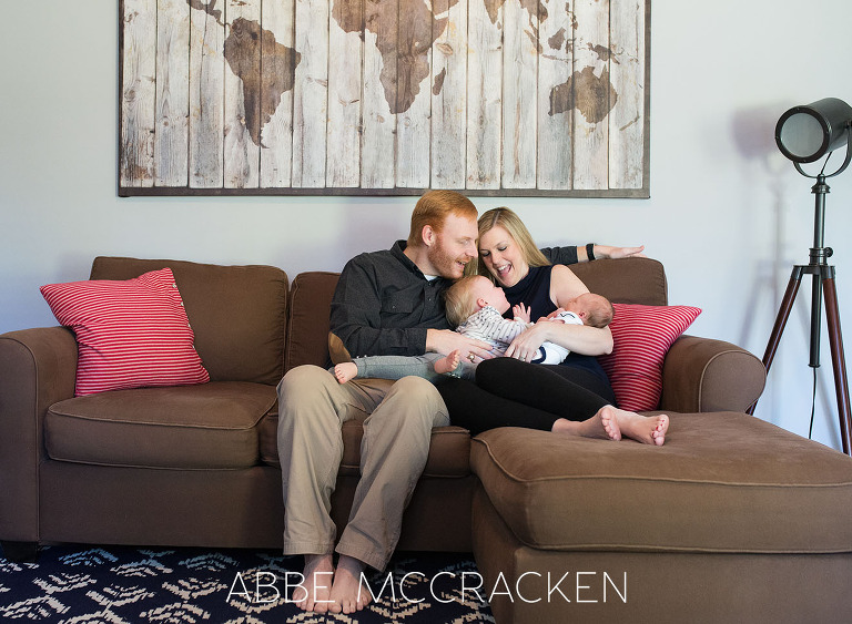 Candid image of a family of four snuggling on the couch taken during a newborn lifestyle session for a baby boy