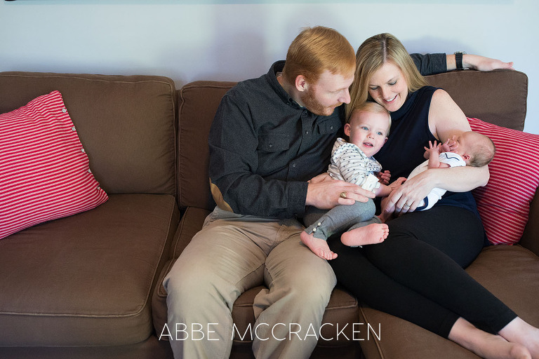 Candid image of a family of four snuggling on the couch taken during a newborn lifestyle session