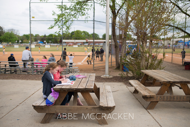 Image of older siblings doing homework at the South Charlotte baseball fields