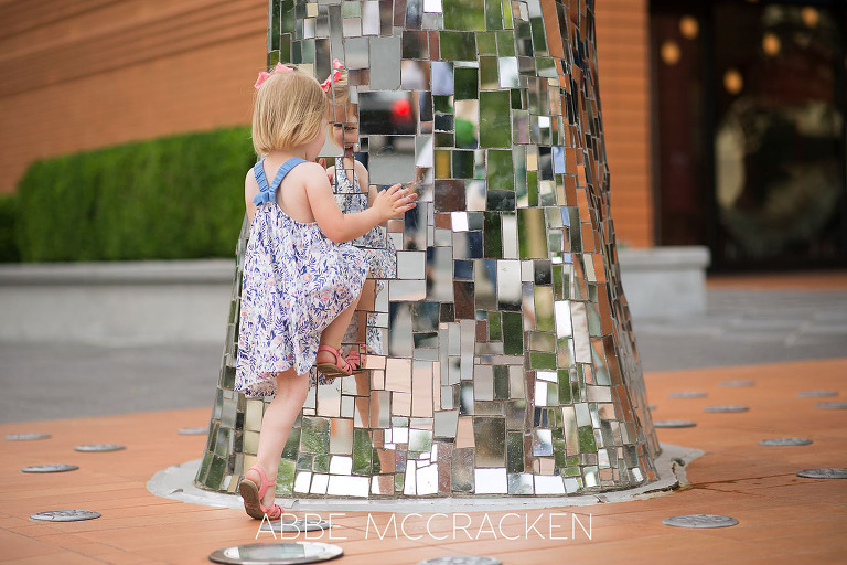 Three year old girl playing with her reflection in The Firebird outside the Bechtler Museum of Modern Art in Charlotte, NC