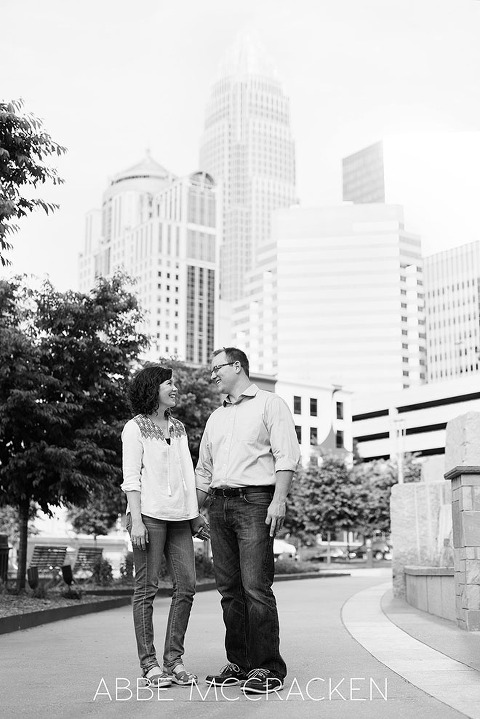 Image of parents taking a moment for themselves during a family photo shoot. Uptown Charlotte skyline is in the background.