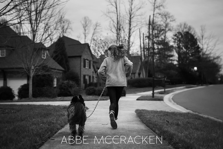 Black and white image of a girl and dog running before dark