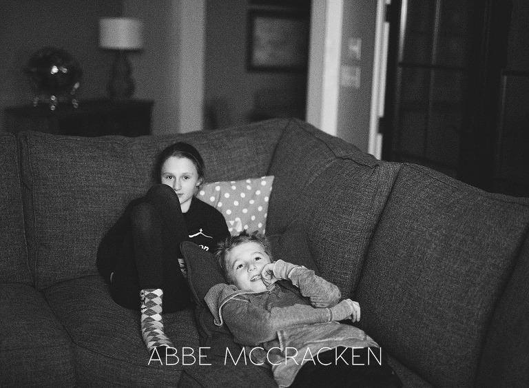 black and white, low light image of siblings at home watching a movie; embracing the grain