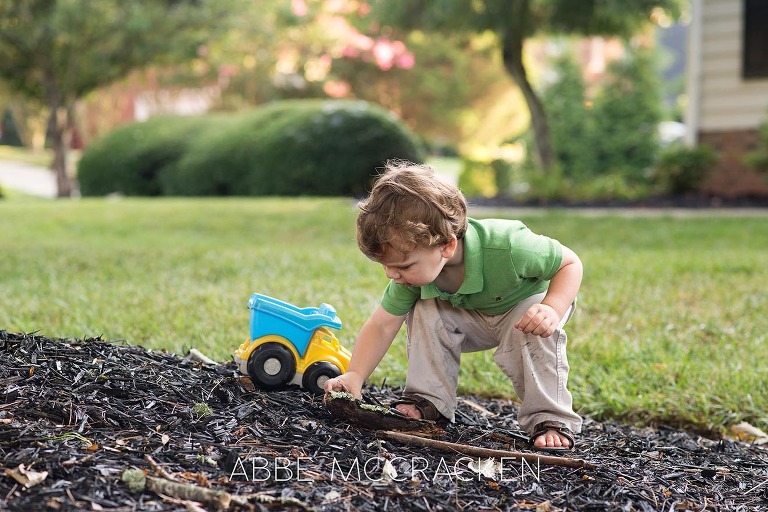 Toddler boy playing with a truck in his yard