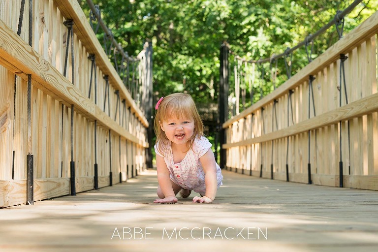 two-year-old red-headed girl crawling on the newly rebuilt bridge in Charlotte's Freedom Park