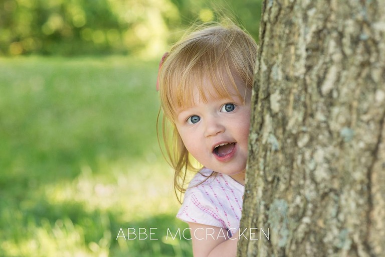 Adorable two-year-old girl played peek-a-boo with Charlotte NC child and family photographer Abbe McCracken