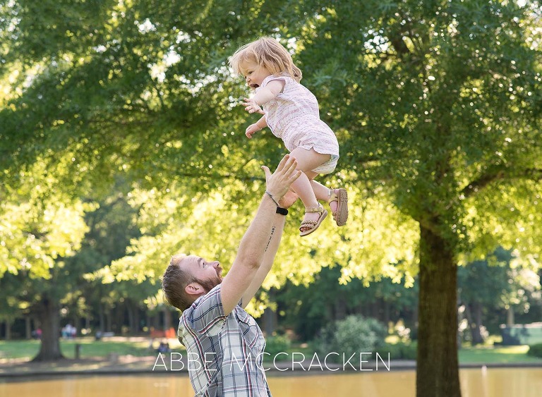 Family picture of a father tossing his two-year-old daughter into the air at Freedom Park