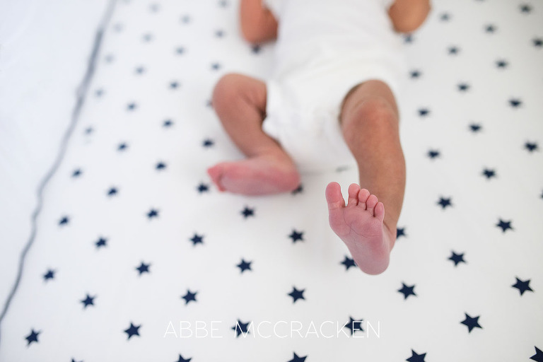 Image of a newborn baby boy foot up in the air as he lays in his crib