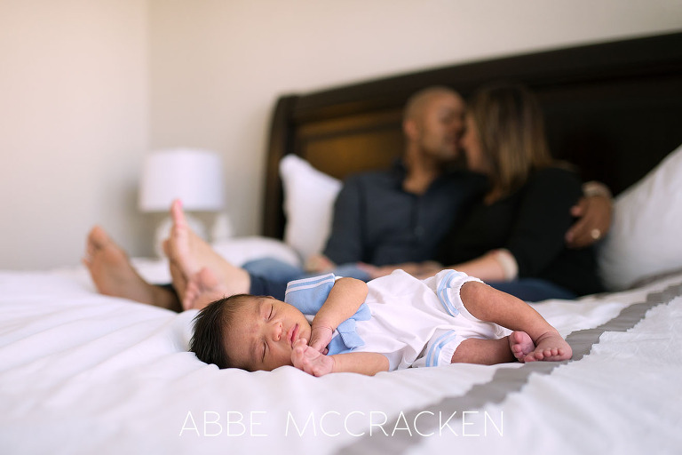 Family of 3! Newborn baby boy sleeping on master bed while parents enjoy a quiet moment.