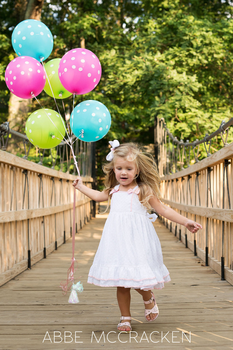 Little girl celebrates turning 3 years old girl with colorful balloons. Pictured in Charlotte's Freedom Park.
