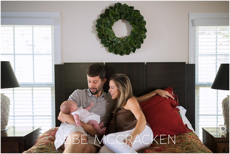 Newborn lifestyle photography session - parents and baby on bed in family home