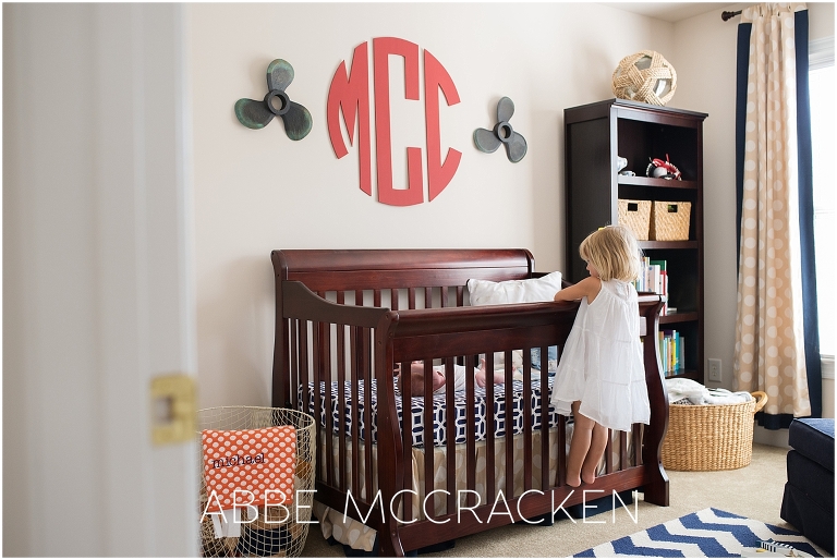 Newborn lifestyle photography session - big sister peeking over crib to see baby brother