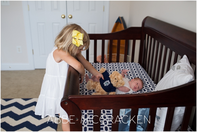 Newborn lifestyle photography session - big sister handing baby brother a teddy bear